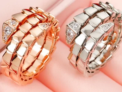 Dos anillos en espiral, uno rosado y otro plateado, sobre un expositor rosa