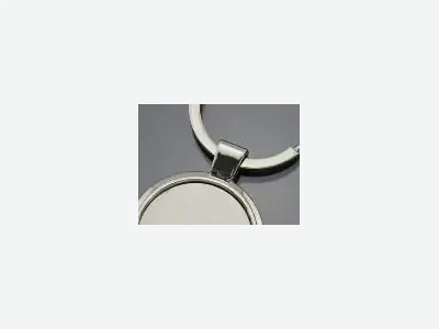 Llavero metálico de aro y medalla redonda lisa, sobre fondo gris