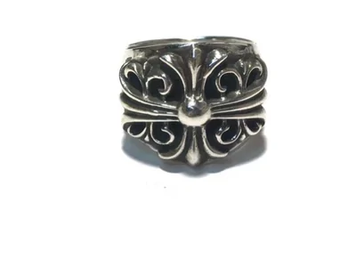 Anillo ancho de tono plateado oscuro con una flor de lis en relieve, sobre fondo blanco