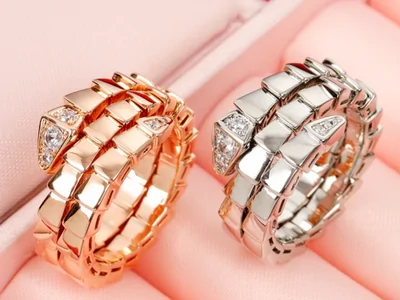 Dos anillos en espiral, uno rosado y otro plateado, sobre un expositor rosa