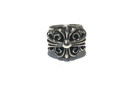 Anillo ancho de tono plateado oscuro con una flor de lis en relieve, sobre fondo blanco